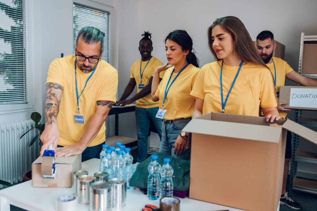 Gruppe von multirassischen Freiwilligen, die Menschen in einem Wohltätigkeitszentrum helfen.