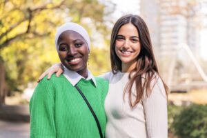 multirassisches Paar von zwei jungen Frauen, die lächelnd in die Kamera schauen, Konzept der Freundschaft und des Glücks